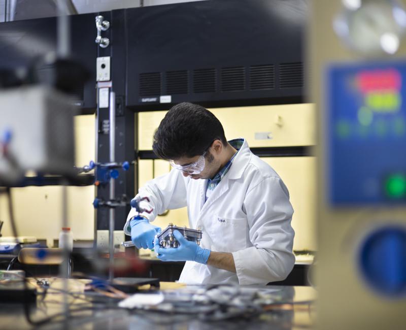 A student researcher works on a fuel cell in a chemical engineering lab