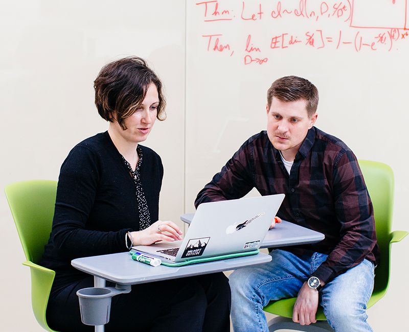 A faculty member talking to a student in an open study space