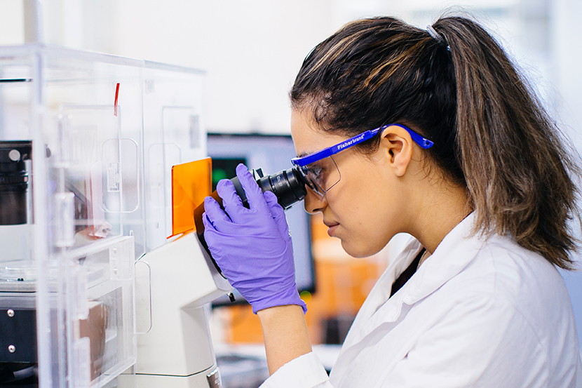 Undergraduate students in a lab looking into a microscope