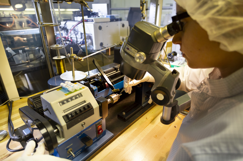 A student researcher winds a coil for a brain implant to help the blind see