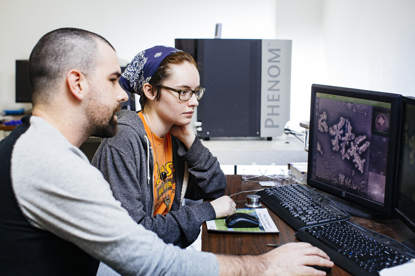 A physics student and professor analyze an image on a computer