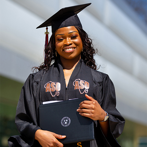 student graduating holding up diploma