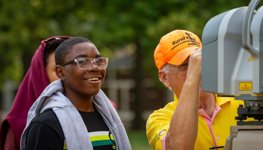 A summer program participant smiles during the surveying summer program in July 2023