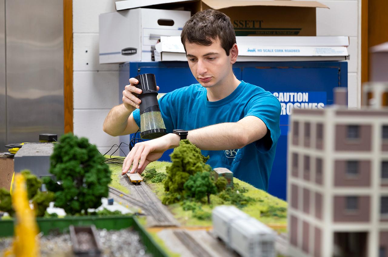Daniel Rappoport adds grass to this section of model railroad in Alumni Hall. 