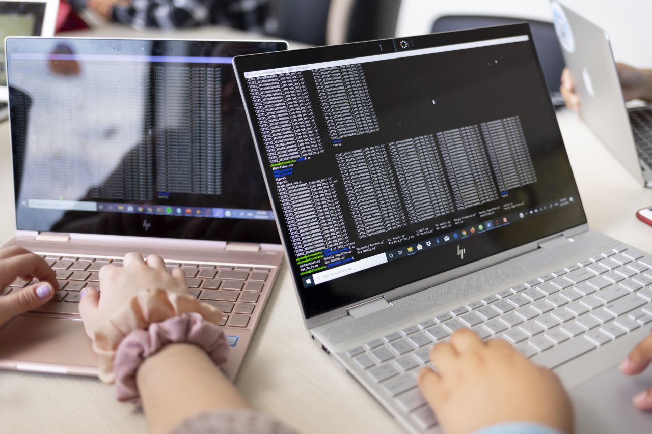 Two people type on laptops.