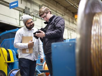 Photo of two people looking at handheld device in a factory
