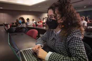 A student in a Chicago-Kent College of Law listens in class while taking notes on a lapton