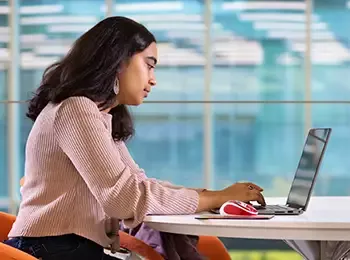 Female student sitting at table using laptop