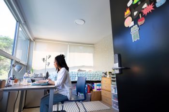 An Illinois Tech student works on her laptop in the Kacek Hall residence hall on Mies Campus