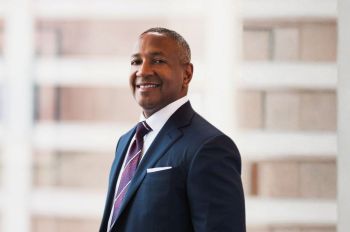 A man in a suit and tie smiles in a portrait.