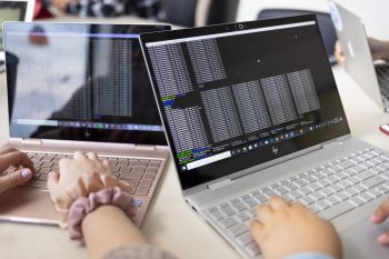 Two people type on laptops.