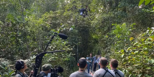 Illinois Tech students and judges standing in forest looking up at drone