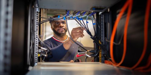 Illinois Tech College of Computing male student looking inside of computer