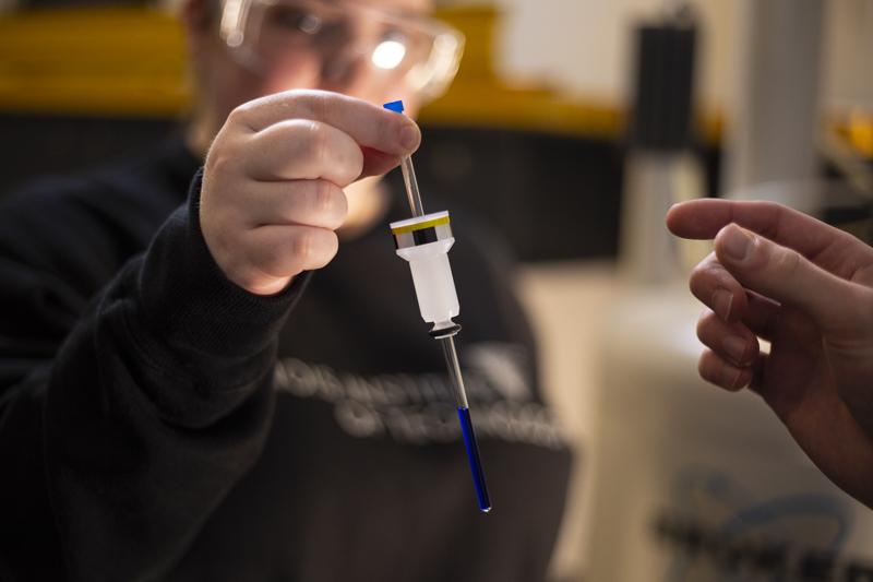 A researcher holds a chemical compound to be analyzed