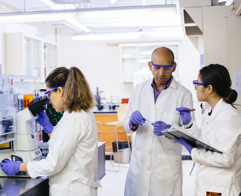 Photo of Assistant Professor Abhinav Bhushan and two students in the laboratory