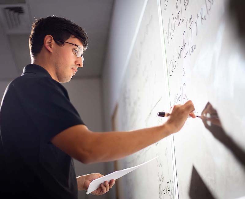 Photo of Esteban Lopez writing equation on whiteboard