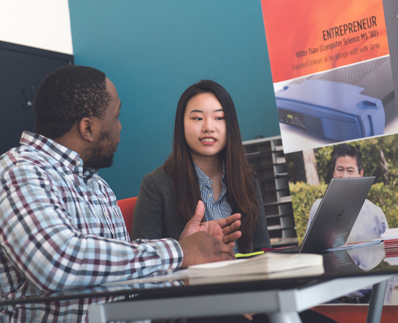 Counselor sitting down at desk with student advising them