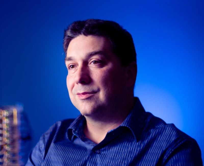 Ioan Raicu sits in the foreground with a blue background